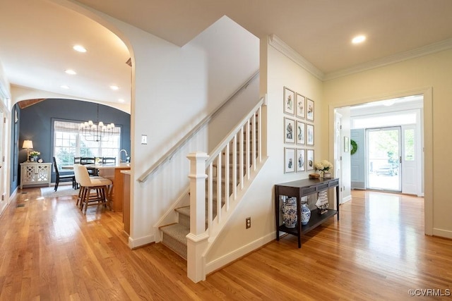 staircase with arched walkways, wood finished floors, and a wealth of natural light