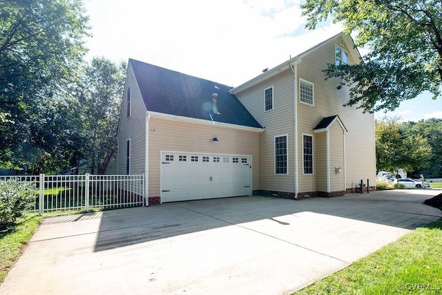 view of side of home featuring driveway, crawl space, an attached garage, and fence