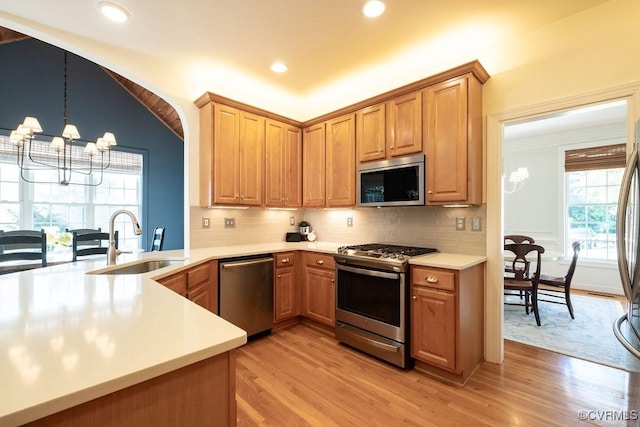 kitchen with a chandelier, a sink, light countertops, appliances with stainless steel finishes, and tasteful backsplash