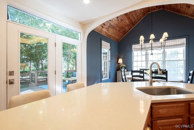 kitchen featuring a notable chandelier, lofted ceiling, light countertops, a healthy amount of sunlight, and a sink