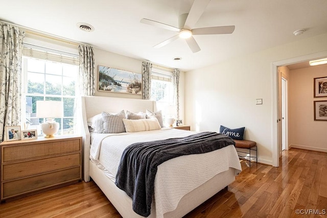 bedroom featuring light wood finished floors, baseboards, visible vents, and ceiling fan