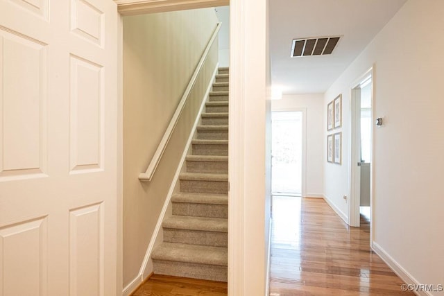 stairs with baseboards, visible vents, and wood finished floors