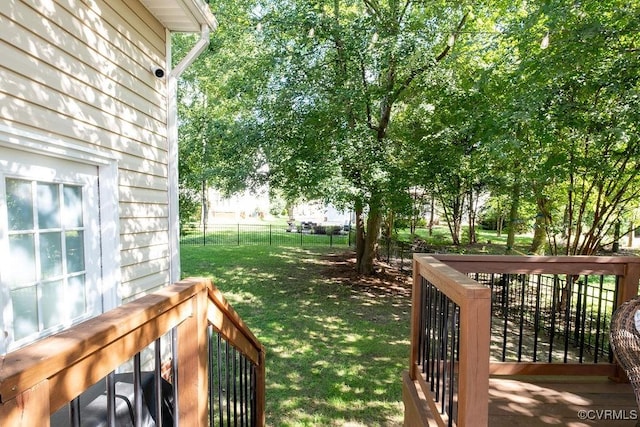 wooden terrace featuring fence and a yard