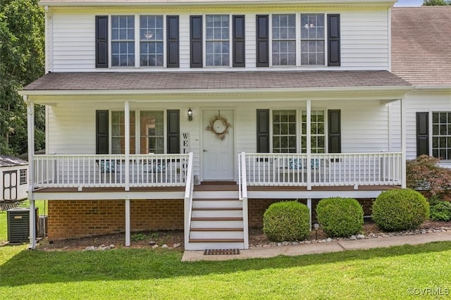 view of front of home featuring central air condition unit, covered porch, and a front lawn