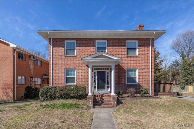 view of front of home featuring brick siding, a chimney, and a front lawn