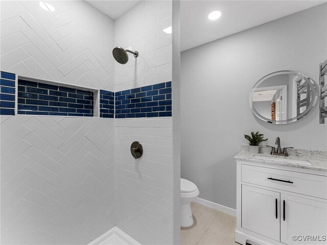 full bath with toilet, vanity, baseboards, a tile shower, and tile patterned floors