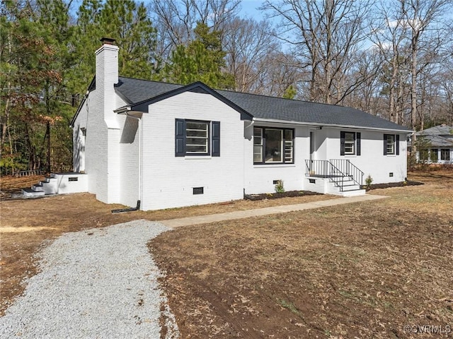 ranch-style house featuring brick siding, a shingled roof, driveway, crawl space, and a chimney