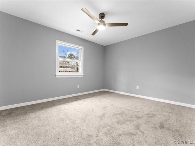 carpeted spare room with visible vents, a ceiling fan, and baseboards