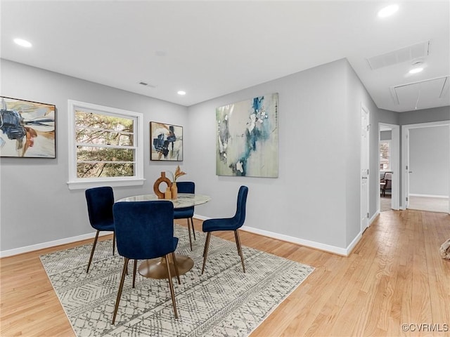 dining room featuring attic access, visible vents, baseboards, and wood finished floors