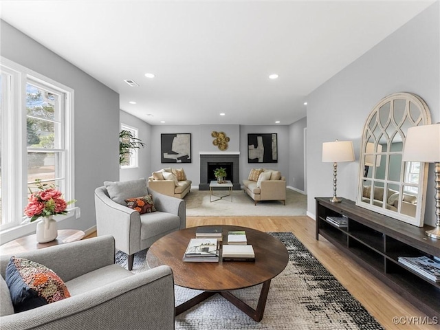 living area with recessed lighting, a fireplace, visible vents, baseboards, and light wood-type flooring