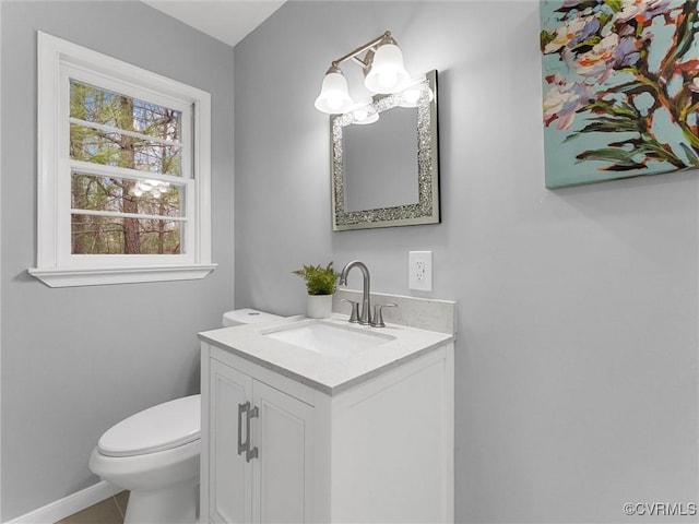 half bath featuring toilet, tile patterned floors, baseboards, and vanity