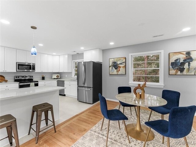 kitchen featuring a breakfast bar, stainless steel appliances, light countertops, visible vents, and white cabinetry