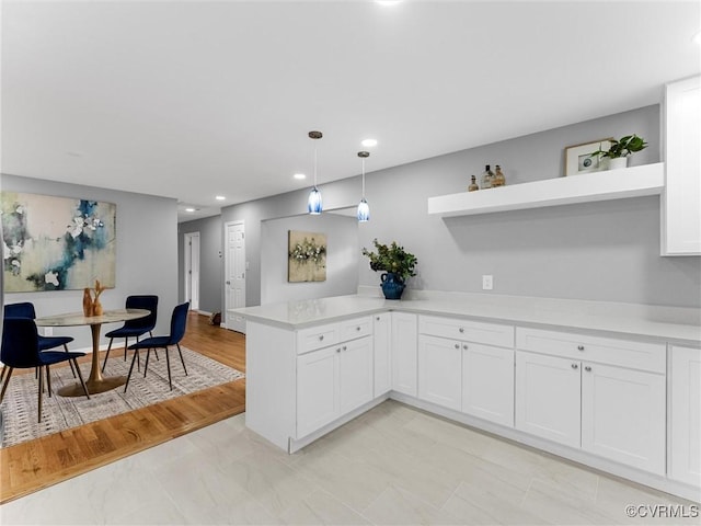 kitchen featuring white cabinets, decorative light fixtures, a peninsula, light countertops, and open shelves