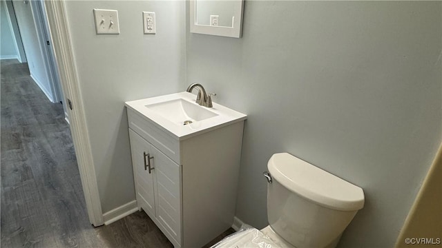 bathroom with toilet, baseboards, wood finished floors, and vanity