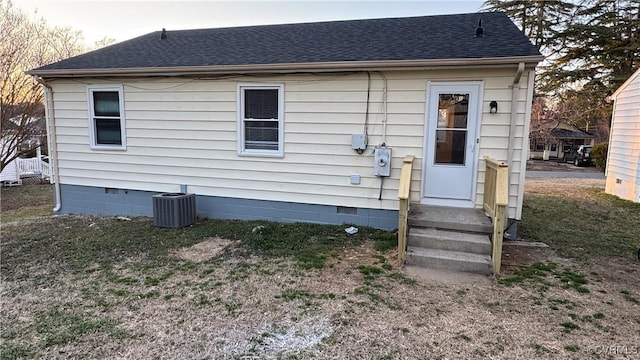 rear view of house featuring roof with shingles, central AC unit, and crawl space