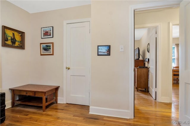 hall with light wood-type flooring and baseboards