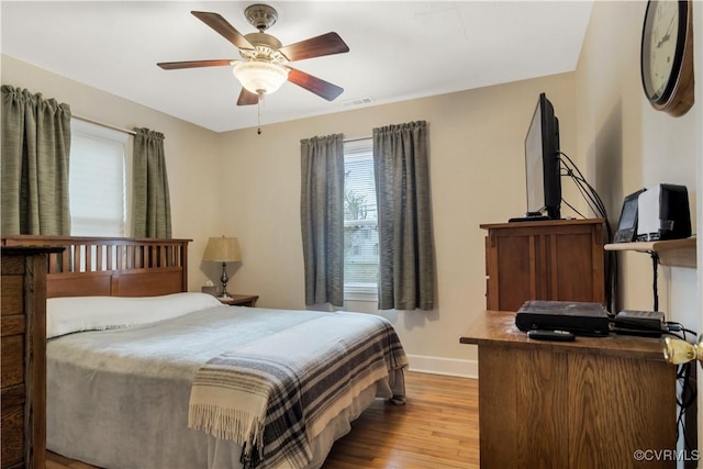 bedroom featuring ceiling fan, wood finished floors, visible vents, and baseboards