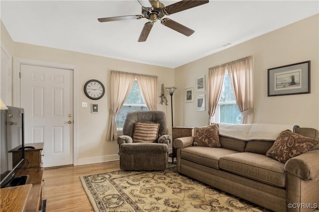 living room with ceiling fan, light wood finished floors, a wealth of natural light, and baseboards