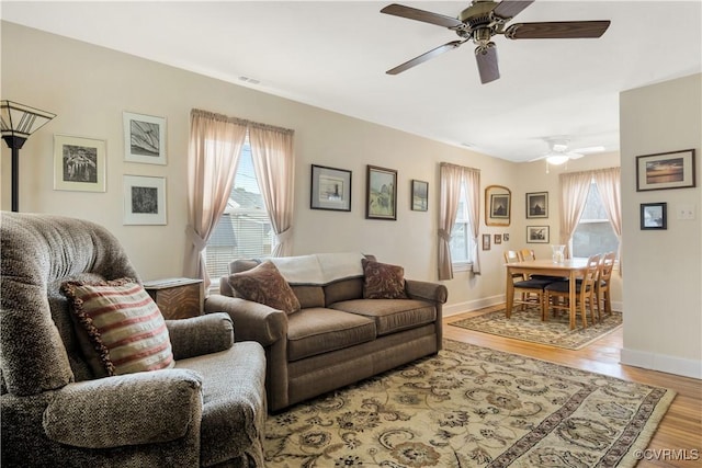 living room featuring light wood finished floors, plenty of natural light, visible vents, and baseboards