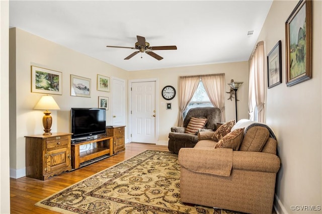 living area featuring baseboards, visible vents, a ceiling fan, and wood finished floors