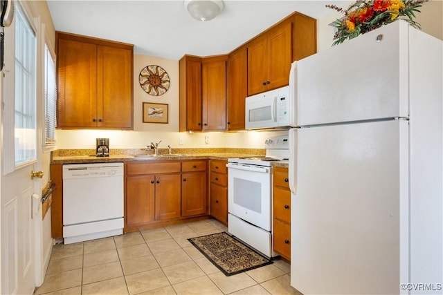 kitchen with white appliances, plenty of natural light, brown cabinetry, and a sink