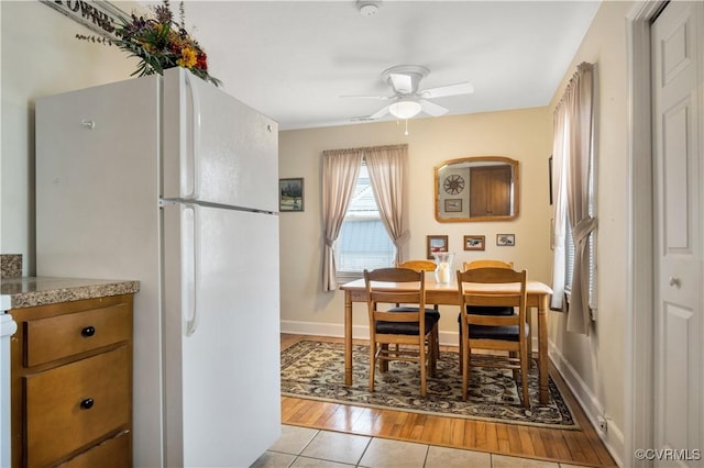 dining room with light wood finished floors, ceiling fan, and baseboards