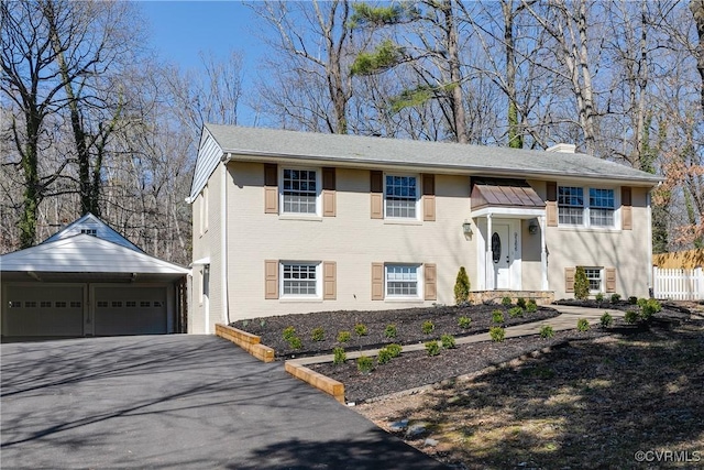 split foyer home with a garage, brick siding, a chimney, and an outdoor structure