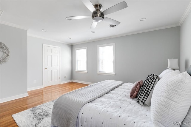 bedroom with baseboards, visible vents, ceiling fan, wood finished floors, and crown molding