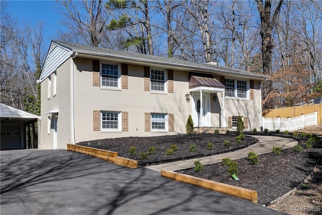 raised ranch with a garage, brick siding, and fence