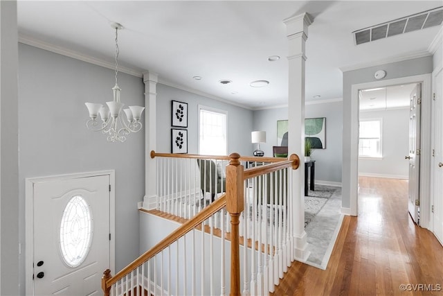 interior space with baseboards, visible vents, wood finished floors, crown molding, and an upstairs landing