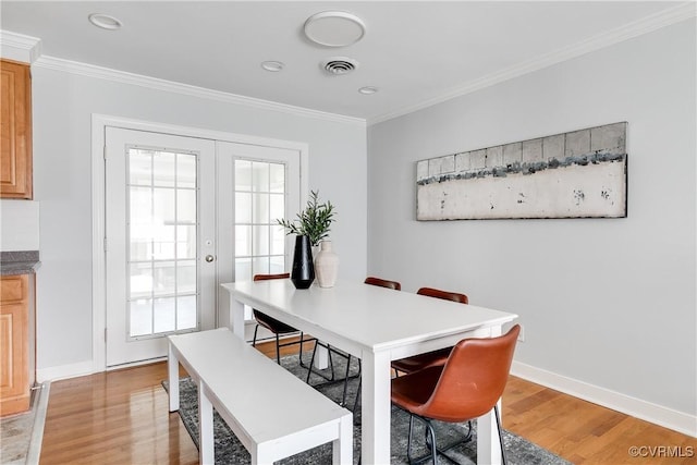 dining room featuring light wood-type flooring, visible vents, french doors, and ornamental molding