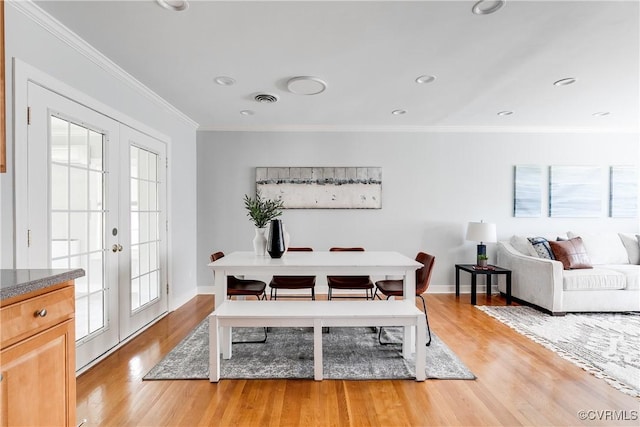 dining room featuring wood finished floors, visible vents, baseboards, ornamental molding, and french doors