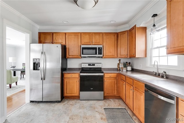 kitchen featuring pendant lighting, stainless steel appliances, a sink, brown cabinets, and crown molding