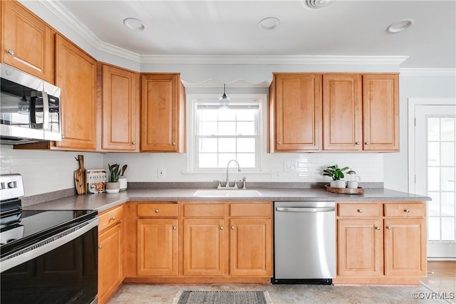 kitchen featuring brown cabinets, crown molding, stainless steel appliances, dark countertops, and a sink