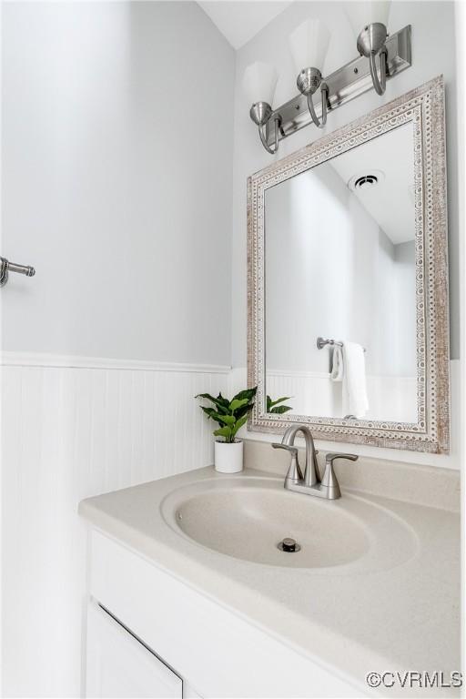 bathroom with a wainscoted wall, visible vents, and vanity