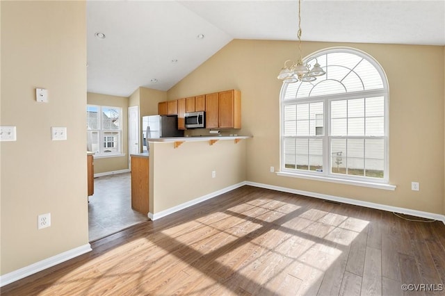 kitchen featuring pendant lighting, light countertops, appliances with stainless steel finishes, a peninsula, and a kitchen bar