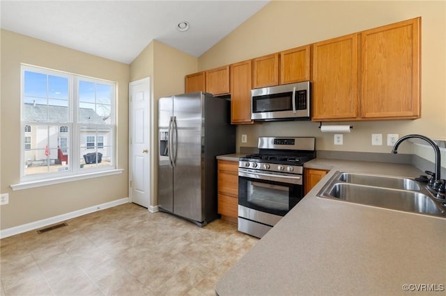 kitchen with visible vents, lofted ceiling, appliances with stainless steel finishes, light countertops, and a sink