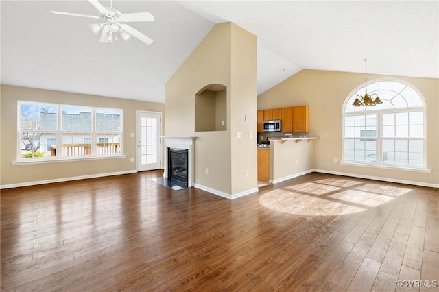 unfurnished living room with dark wood-style floors, lofted ceiling, a fireplace with flush hearth, baseboards, and ceiling fan with notable chandelier