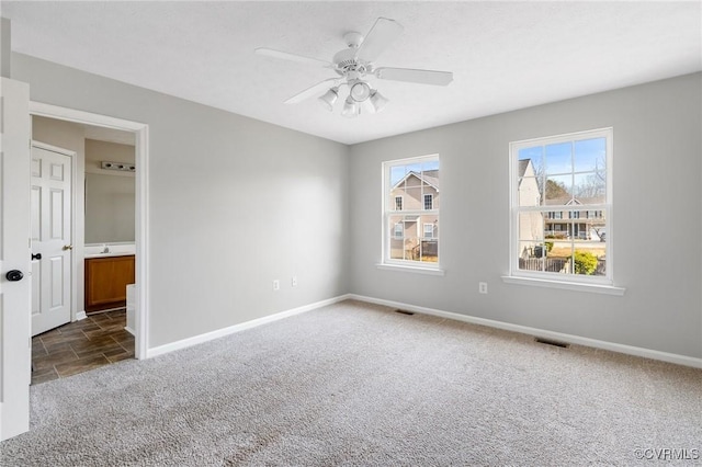 spare room with visible vents, dark carpet, baseboards, and ceiling fan