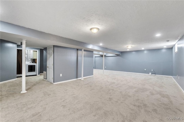 finished below grade area with a textured ceiling, recessed lighting, light colored carpet, baseboards, and washer / clothes dryer