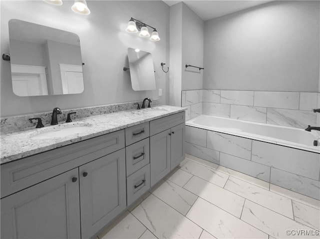 bathroom featuring marble finish floor, double vanity, a sink, and a bath