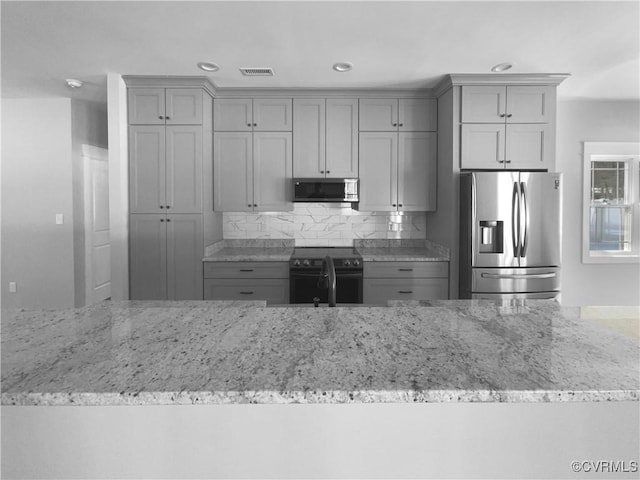 kitchen with appliances with stainless steel finishes, gray cabinets, visible vents, and light stone countertops