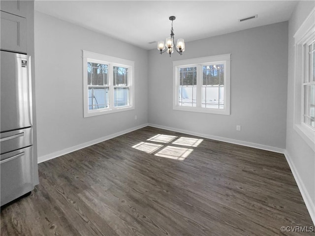 unfurnished dining area featuring dark wood-style floors, baseboards, visible vents, and a notable chandelier