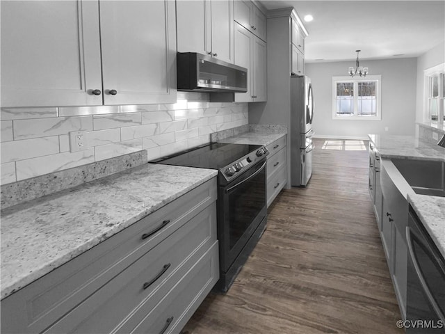 kitchen featuring light stone counters, stainless steel appliances, a sink, tasteful backsplash, and pendant lighting