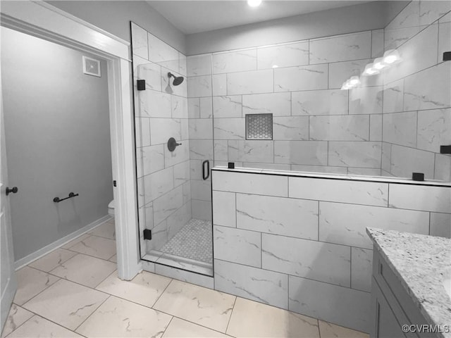 bathroom featuring toilet, vanity, baseboards, marble finish floor, and a stall shower