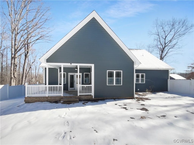 snow covered back of property featuring fence and a porch