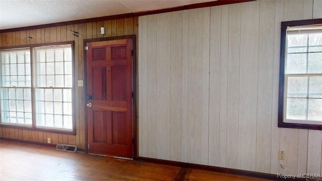 spare room featuring dark wood-style flooring, visible vents, wood walls, and baseboards