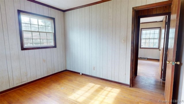 unfurnished room with light wood-style floors, crown molding, and baseboards