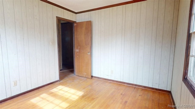 spare room featuring baseboards, ornamental molding, and wood finished floors