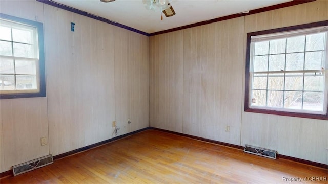 spare room with light wood finished floors, visible vents, and a wealth of natural light